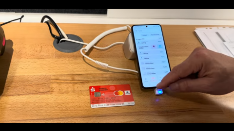 Ein Tisch mit einer Sparkassen-EC-Karte sowie einem Smartphone, dass eine Bezahlapp anzeigt.