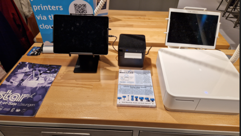 Ein Tisch, auf dem verschiedene elektronische Geräte (Tablet, Kassenbondrucker) stehen